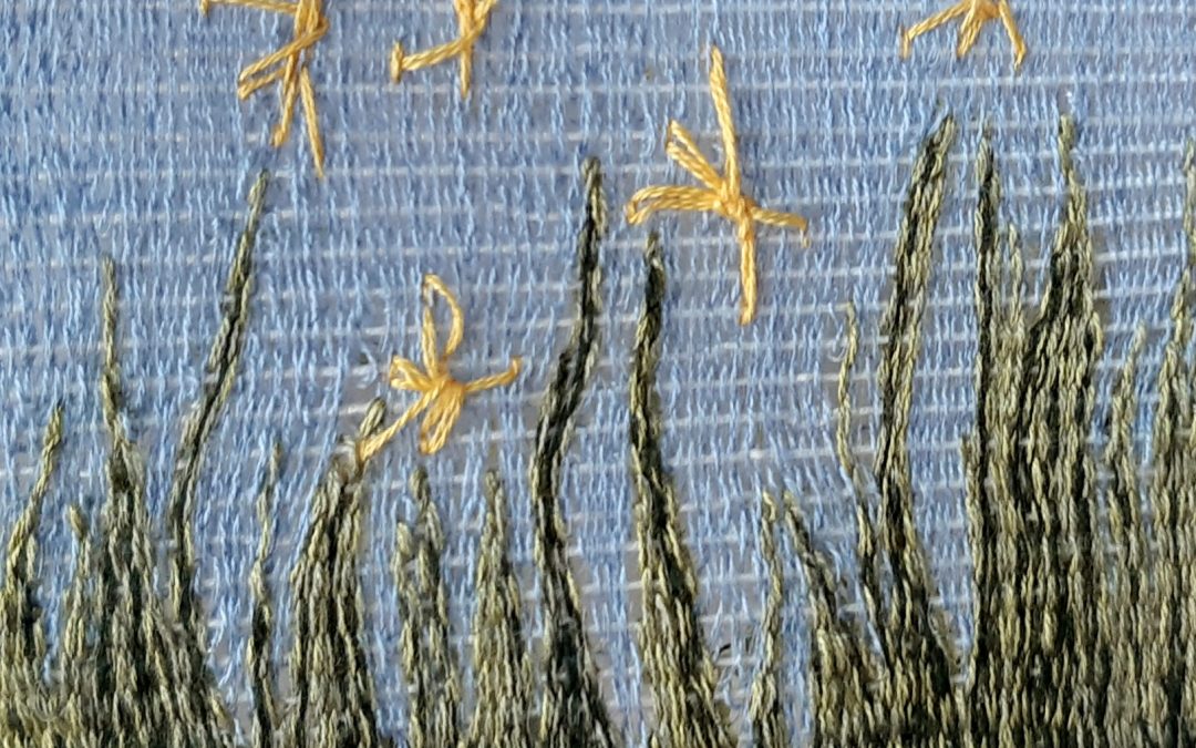 A small woven tapestry depicting a meadow scene of grasses and yellow flowers