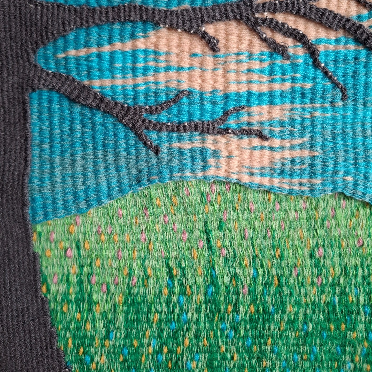 Example of tapestry weaving techniques used to create a blended sky with teal and peach tones, and a speckled green meadow, demonstrating tonal transitions in woven art.
